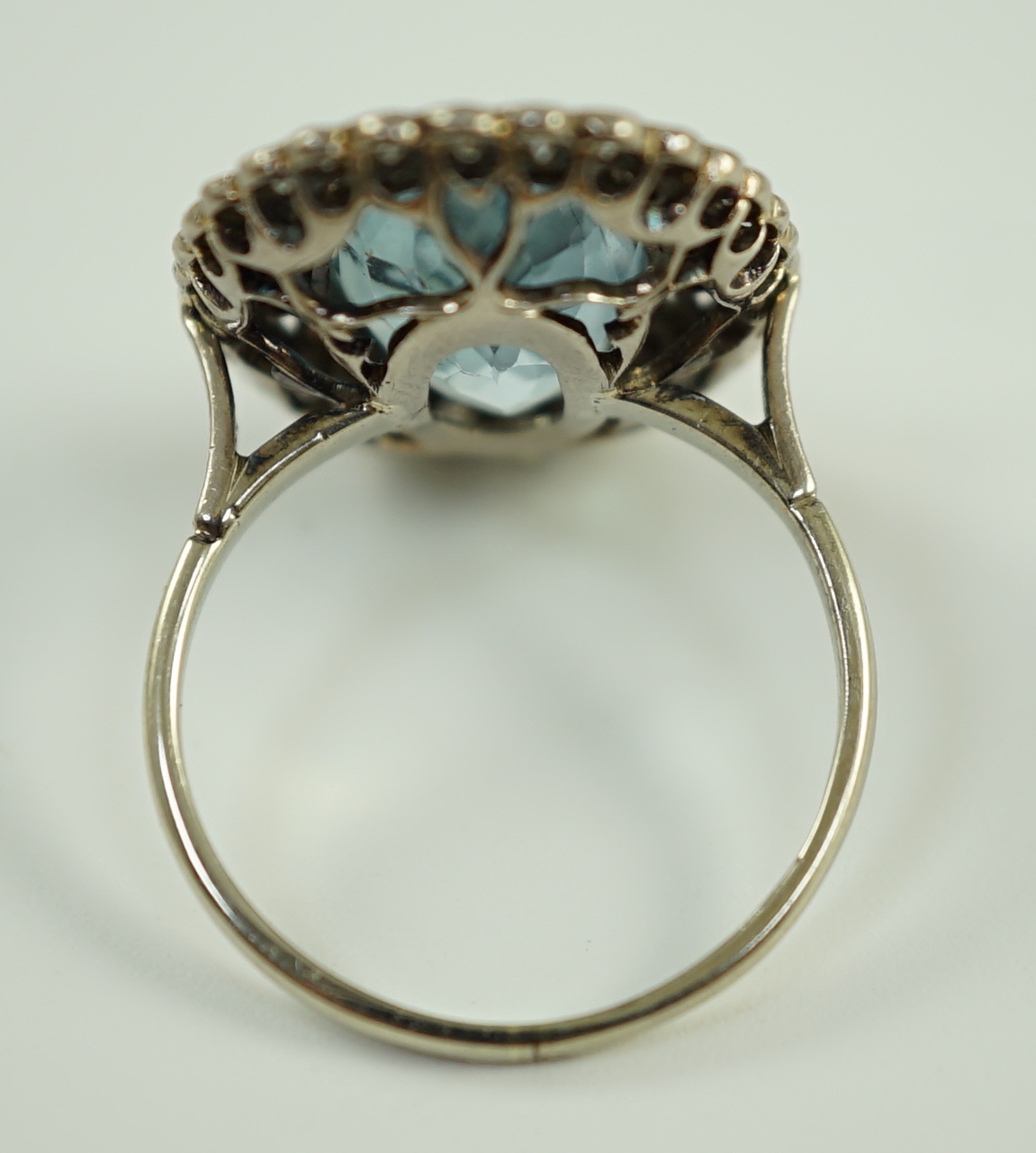 An 18ct white gold and single stone oval cut aquamarine set dress ring, with brilliant cut diamond set border